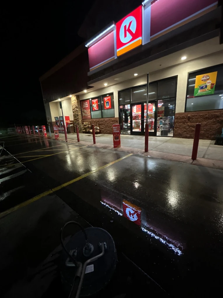 Commercial storefront with clean wet parking lot at night